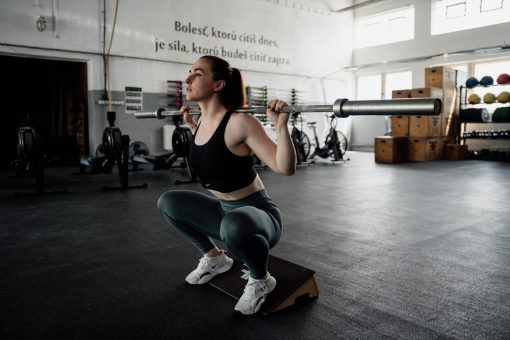 Žena, ktorá cvičí so vzpieračskou tyčou Forward Fitness
